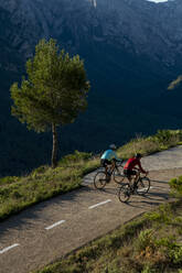 Ältere Radfahrer fahren Fahrräder auf der Straße vor einem Berg - AMNF00091