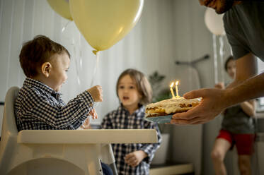 Vater hält Kuchen und feiert den Geburtstag seines Sohnes zu Hause - ANAF00841