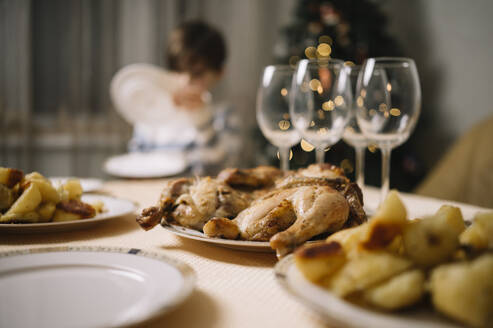 Essen und Weingläser auf einem Tisch mit einem Jungen im Hintergrund - ANAF00847