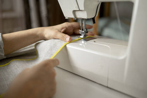 Hands of woman stitching cloth using sewing machine - ANAF00851