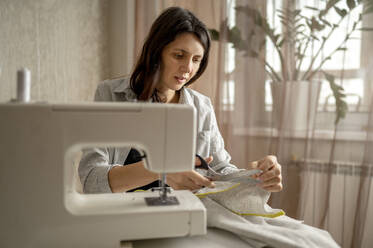 Woman cutting cloth with scissors at home - ANAF00853