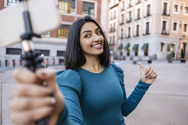 Lächelnde junge Frau nimmt Selfie durch Smartphone in der Stadt - JCCMF08960
