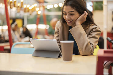 Glückliche junge Frau mit Tablet-Computer in einem Café - JCCMF08996