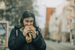 Teenager-Mädchen isst Burger auf der Straße - VSNF00301