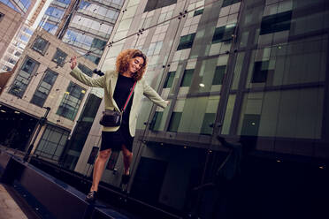 Smiling businesswoman balancing on bench near building - PWF00665