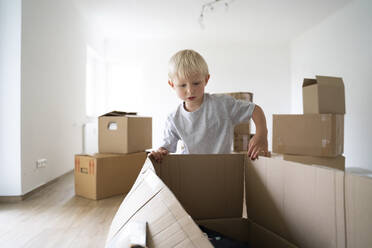 Boy opening cardboard box at home - NJAF00191