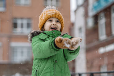 Niedlicher Junge genießt den Schneefall im Winter - ANAF00861