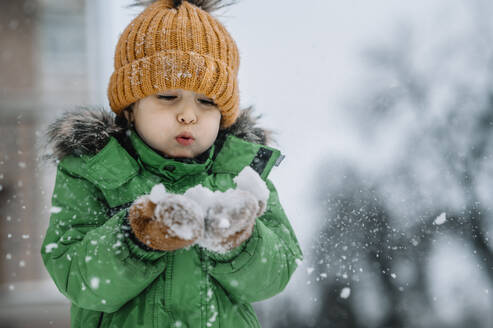 Junge beim Schneeschaufeln, der im Winter Spaß hat - ANAF00862