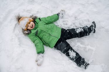 Niedlicher Junge macht Schneeengel - ANAF00869