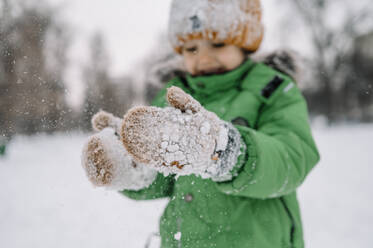 Junge mit Handschuhen spielt mit Schnee - ANAF00870