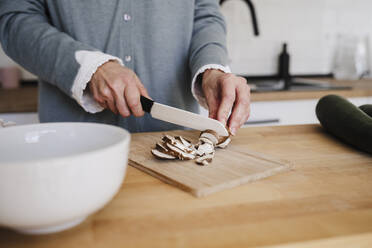 Hände einer Frau, die in der Küche Pilze mit einem Messer schneidet - EBBF07656