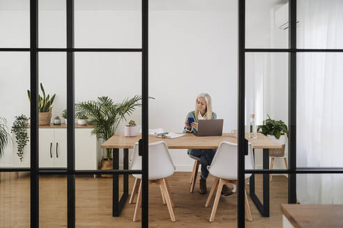 Freiberufler mit Smartphone am Schreibtisch im Home Office - EBBF07675