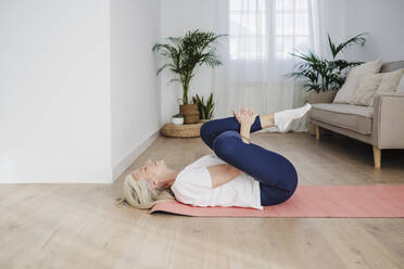 Mature woman exercising in living room - EBBF07745