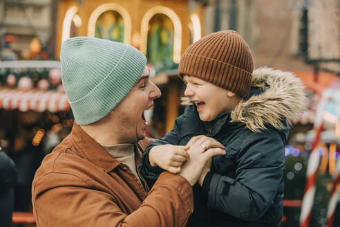 Fröhlicher Vater hat Spaß mit seinem Sohn auf dem Weihnachtsmarkt - VSNF00309