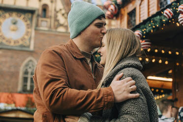 Man kissing woman on forehead at Christmas market - VSNF00312