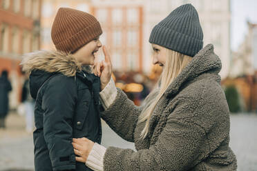 Happy mother touching nose of son and enjoying at Christmas market - VSNF00321