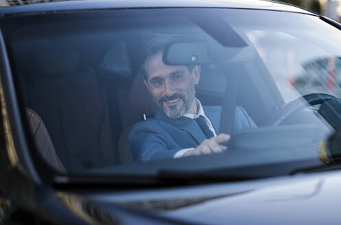 Lächelnd reifen Geschäftsmann Überprüfung GPS durch die Windschutzscheibe des Autos gesehen - OIPF02748