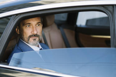 Thoughtful mature businessman sitting in backseat of car - OIPF02750