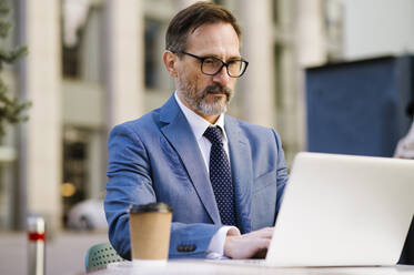 Mature businessman working on table at cafe - OIPF02764