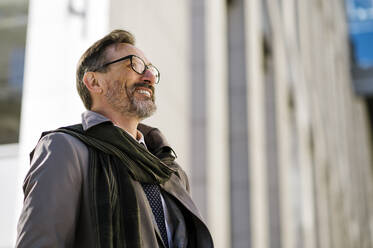 Lächelnder reifer Geschäftsmann mit Brille vor einem Bürogebäude - OIPF02805