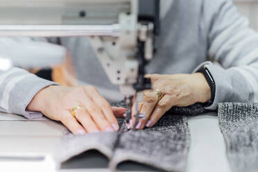 Senior craftswoman using sewing machine in workshop - PGF01430