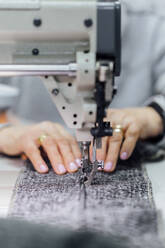 Senior woman using sewing machine in workshop - PGF01431