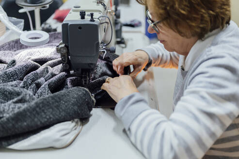 Senior upholsterer working on sewing machine in workshop - PGF01434