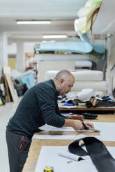 Upholsterer worker cutting fabric at workbench - PGF01437