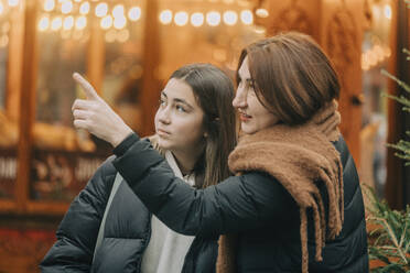 Mother pointing daughter at Christmas market - VSNF00330