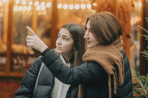 Mutter zeigt auf Tochter auf dem Weihnachtsmarkt - VSNF00330