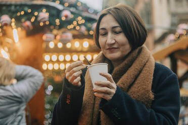 Lächelnde Frau beim Kaffee trinken im Winter - VSNF00333