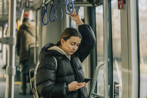 Teenager-Mädchen mit Smartphone in der Straßenbahn - VSNF00342