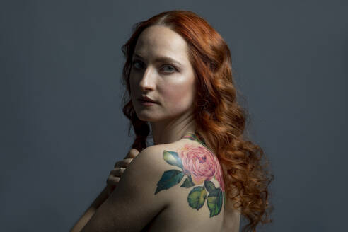 Beautiful woman with flower tattoo against gray background - OSF01327