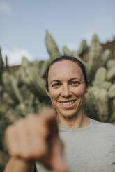 Glückliche Frau gestikuliert im Kaktusgarten - DMGF00963