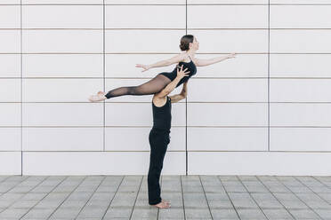 Mann hebt Frau beim Balletttanz vor einer Wand - JRVF03293