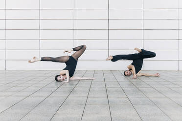 Couple doing headstand with splits in front of wall - JRVF03300