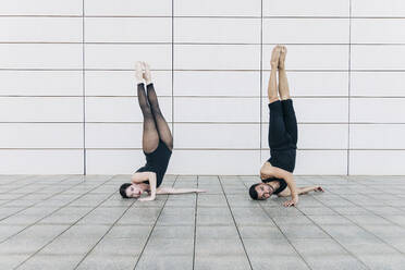 Couple doing headstand together in front of wall - JRVF03301