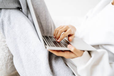 Hand of woman typing on laptop at home - MDOF00515