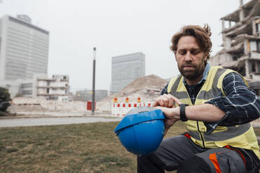 Mature worker checking time on watch at construction site - JOSEF15723