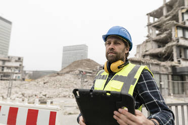 Älterer Arbeiter mit Tablet-PC vor einer Baustelle - JOSEF15755