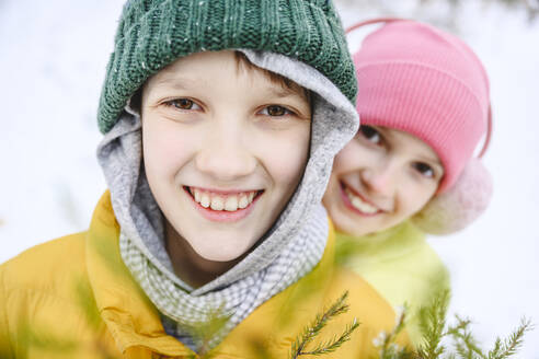 Glückliche Geschwister mit Strickmütze im Schnee - EYAF02515