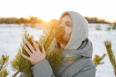 Mann küsst Tannenbaum im Winter - EYAF02520