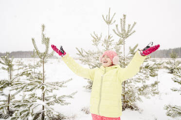 Fröhliches Mädchen, das Schnee wirft und den Winterurlaub genießt - EYAF02523
