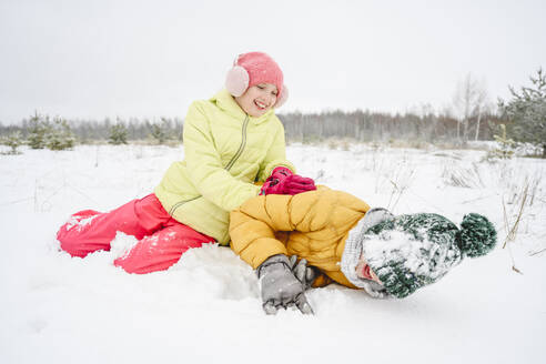 Happy girl playing and having fun with brother in snow - EYAF02529