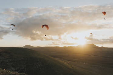 Fallschirme fliegen unter bewölktem Himmel bei Sonnenuntergang - DMGF00973