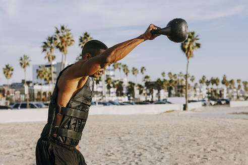 Sportler beim Training mit der Kettlebell am Strand - OIPF02823