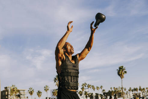 Älterer Mann fängt Kettlebell unter Himmel - OIPF02825