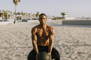 Aktiver reifer Mann, der mit einem Sportball am Strand trainiert - OIPF02835