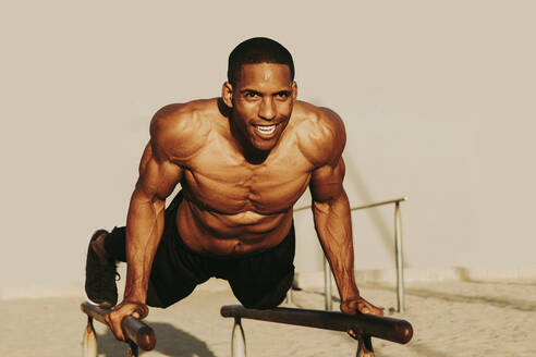 Smiling mature athlete exercising on parallel bars - OIPF02845