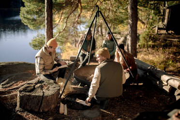 Gemischtrassige Freunde verbringen ihre Freizeit an einer Feuerstelle beim Camping - MASF34195